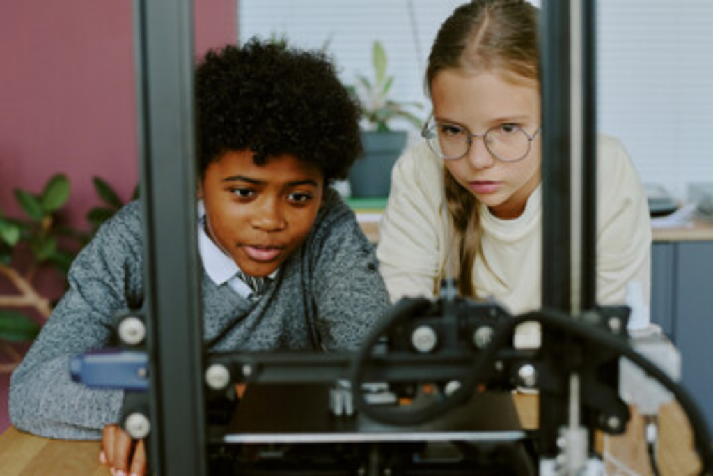 Two kids watching a 3D Printer